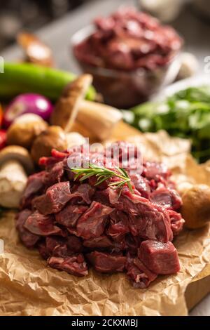 Geschnittenes Hirschfleisch, das für den Eintopf von Waldpilzen zubereitet wird Kräuter und Gemüse Stockfoto