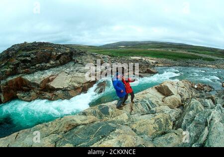 Kaukasische Männer und Frauen besuchen den Wasserfall in der Nähe von Wager Bay an der Westküste von Hudson Bay, Nunavut, Kanada. Dies ist 50 Meilen südlich des Polarkreises. Stockfoto