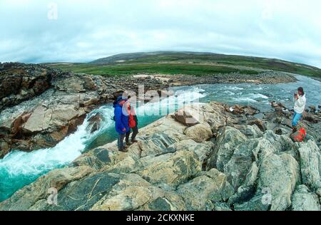 Kaukasische Männer und Frauen besuchen den Wasserfall in der Nähe von Wager Bay an der Westküste von Hudson Bay, Nunavut, Kanada. Dies ist 50 Meilen südlich des Polarkreises. Stockfoto