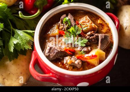 Schüssel Gulaschsuppe mit Fleisch, Kartoffeln, Chilis und Petersilie Stockfoto