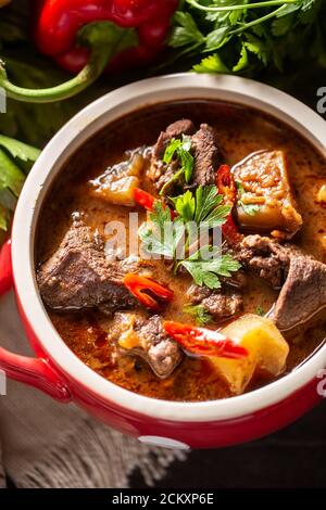 Schüssel Gulaschsuppe mit Fleisch, Kartoffeln, Chilis und Petersilie Stockfoto