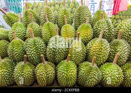 Berühmt riechende Durian-Frucht, zum Verkauf auf einem Nachtmarkt in Singapur. Der kränklich süße Geruch dieser Frucht ist so intensiv, dass sie von einigen öffentlichen Verkehrsmitteln und Hotels im tropischen Asien verboten ist. Stockfoto