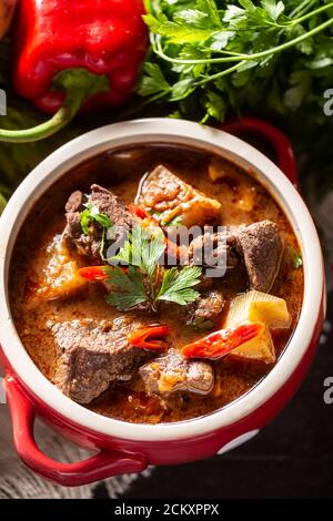 Schüssel Gulaschsuppe mit Fleisch, Kartoffeln, Chilis und Petersilie Stockfoto