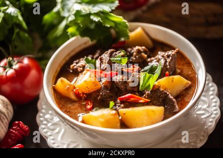 Schüssel Gulasch mit Fleisch, Kartoffeln, Chilis und Petersilie Stockfoto