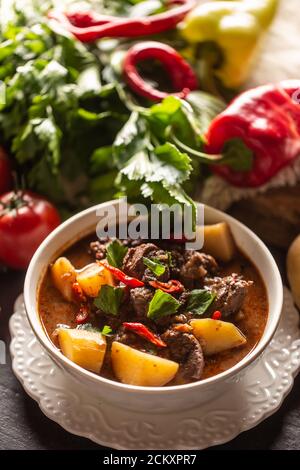 Schüssel Gulasch mit Fleisch, Kartoffeln, Chilis und Petersilie Stockfoto