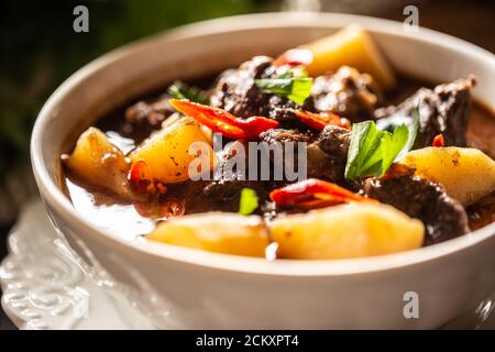 Schüssel Gulasch mit Fleisch, Kartoffeln, Chilis und Petersilie Stockfoto