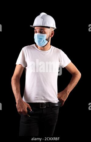 Junge hispanische männliche Bauarbeiter mit Maske stehen Stockfoto