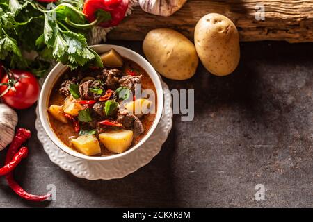 Schüssel Gulasch mit Fleisch, Kartoffeln, Chilis und Petersilie Stockfoto