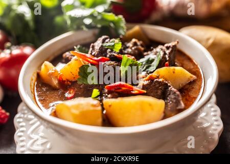 Schüssel Gulascheintopf mit Fleisch, Kartoffeln, Chilis und Petersilie Stockfoto