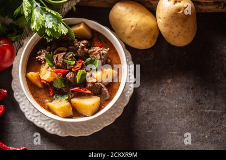 Schüssel Gulasch mit Fleisch, Kartoffeln, Chilis und Petersilie Stockfoto