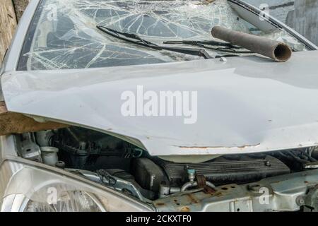 Eisenrohr an einer gebrochenen Windschutzscheibe und Haube. Auto nach dem Unfall, Vorfall. Hooliganismus. Stockfoto