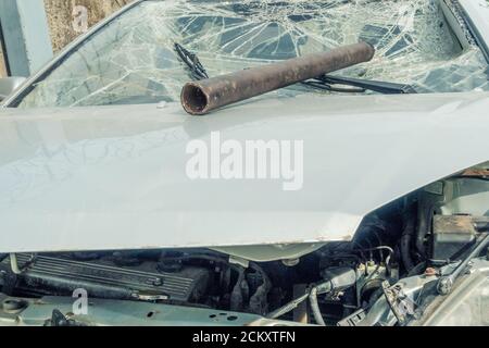 Eisenrohr an einer gebrochenen Windschutzscheibe und Haube. Auto nach dem Unfall, Vorfall. Hooliganismus. Stockfoto
