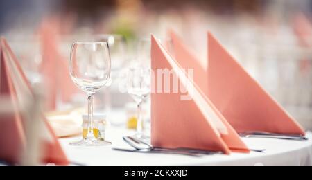 Rosa Servietten gefaltet auf einem festlichen Tisch mit Glaswaren und Besteck daneben Stockfoto