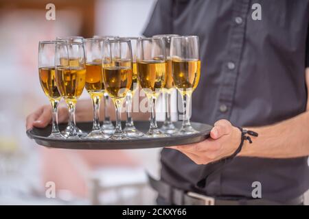 Der Kellner hält ein Serviertablett voll mit Getränken in Champagner Brille Stockfoto