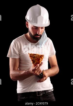 Junge hispanische männliche Bauarbeiter versuchen, Pizza zu essen Stockfoto