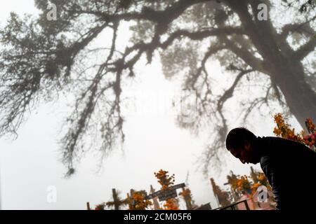 Ein Mexikaner spaziert während der Feierlichkeiten zum Tag der Toten in Ayutla, Mexiko, unter den mit Blumen geschmückten Gräbern auf einem Friedhof. Stockfoto