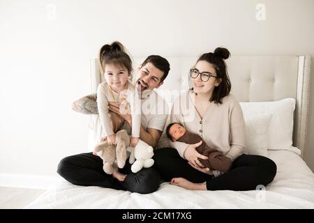 Moderne Millennial Familie mit Kleinkind und Neugeborenen spielt auf Weiß Bett Stockfoto