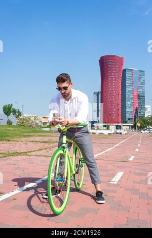 Outdoor Portrait hübscher junger Mann mit Handy und fixed-Gear Fahrrad auf der Straße. Stockfoto