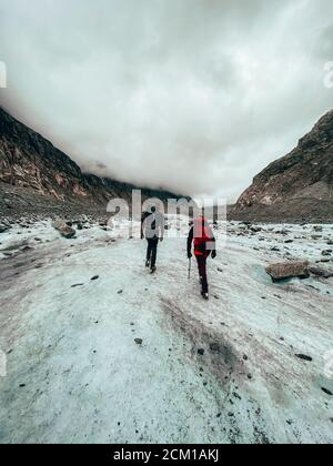 Zwei Bergsteiger wandern auf dem Gletscher unter bewölktem Himmel Stockfoto