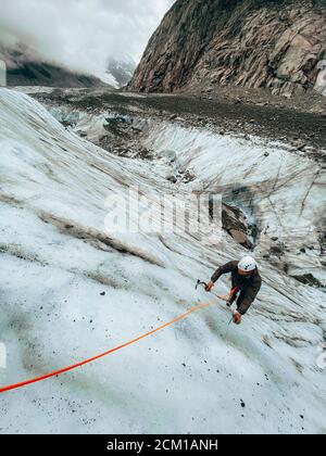 High-Angle-Aufnahme des Mannes, der eine steile Eiswand klettert Mit Eisachsen Stockfoto
