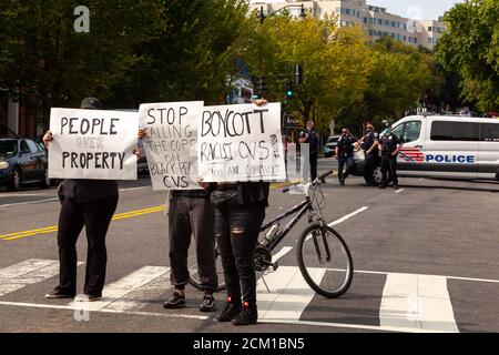 Washington, DC, USA, 16. September 2020. Im Bild: Demonstranten halten Schilder, die sagen, dass CVS rassistisch ist und Menschen über Proterty wertschätzt, während Metropolitan (DC) Polizisten in den Hintergrund schauen. Der Protest fand statt, weil am Tag zuvor der CVS-Store-Manager die Polizei wegen zweier 'suspicious' schwarzer Männer anrief. Sechs Metropolitan (DC) Polizeibeamte nahmen die beiden Männer fest und ließen sie schließlich frei, nachdem eine Durchsuchungsstelle keine gestohlenen Gegenstände gefunden hatte. Angesichts der erheblichen Gefahr von Gewalt, wenn die Polizei auf schwarze Männer gerufen werden, kam eine Reihe von Menschen, um gegen die Entscheidung des Managers zu protestieren. Kredit: Allison C Baile Stockfoto