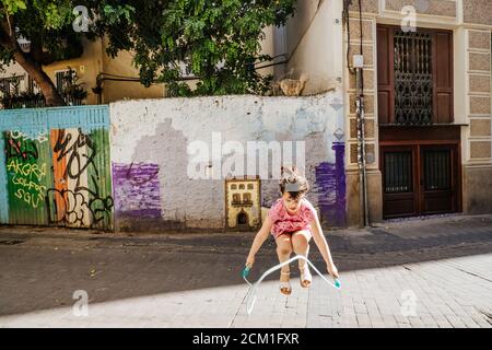 Junges Mädchen spielt mit einem Springseil in einem bunten Straße Stockfoto