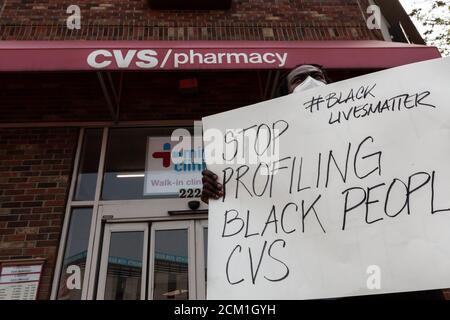 Washington, DC, USA, 16. September 2020. Im Bild: Ein Protestler am Eingang zum CVS hält ein Schild mit der Aufschrift "STOP Profiling Black People, CVS". Der Protest fand statt, weil am Tag zuvor der CVS-Store-Manager die Polizei wegen zweier 'suspicious' schwarzer Männer anrief. Sechs Metropolitan (DC) Polizeibeamte nahmen die beiden Männer fest und ließen sie schließlich frei, nachdem eine Durchsuchungsstelle keine gestohlenen Gegenstände gefunden hatte. Angesichts der erheblichen Gefahr von Gewalt, wenn die Polizei auf schwarze Männer gerufen werden, kam eine Reihe von Menschen, um gegen die Entscheidung des Managers zu protestieren. Kredit: Allison C Bailey/Alamy Stockfoto