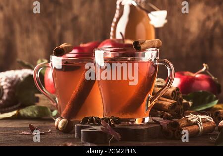 Heißer Apfelessig mit Zimtstangen, Nelken und Anis auf Holzgrund. Traditionelle Herbstgetränke, Wintergetränke und Cocktails Stockfoto