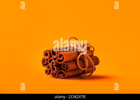 Zimtstangen gebunden mit Jute Seil auf orangefarbenem Hintergrund Stockfoto