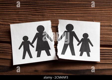 Beziehungen Brechen. Scheidung in einer Familie mit Kindern. Das Papier wird mit dem Symbol des Vaters und der Frau mit Kind in zwei Hälften gerissen. Stockfoto