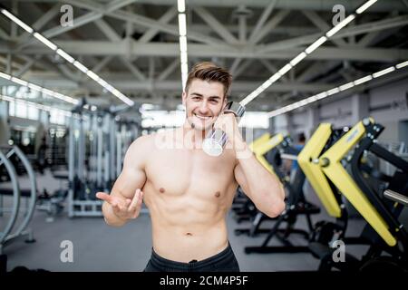 Schöner kaukasischer Gewichtheber mit gut ausgerüsteter Turnhalle, die Spaß beim Ausruhen zwischen den Trainings hat. Stockfoto