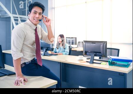 Junge Kundendienstmitarbeiter mit Headsets und Computer arbeiten im Büro. Professionelles Bedienkonzept. Stockfoto