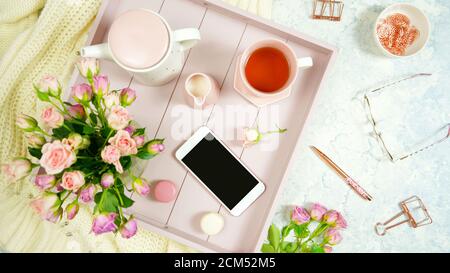 Rouge rosa Thema gemütliche Hygge Desktop-Arbeitsplatz mit Tastatur Smartphone Tee und Rose auf einem stilvollen weißen Marmor texturierten Hintergrund. Top View Blog-Held Stockfoto