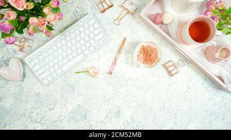 Rouge rosa Thema gemütliche Hygge Desktop-Arbeitsplatz mit Tastatur Smartphone Tee und Rose auf einem stilvollen weißen Marmor texturierten Hintergrund. Top View Blog-Held Stockfoto