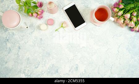 Rouge rosa Thema gemütliche Hygge Desktop-Arbeitsplatz mit Tastatur Smartphone Tee und Rose auf einem stilvollen weißen Marmor texturierten Hintergrund. Top View Blog-Held Stockfoto