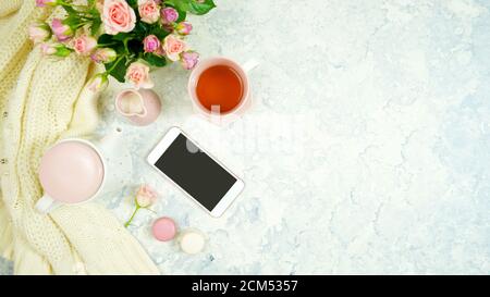 Rouge rosa Thema gemütliche Hygge Desktop-Arbeitsplatz mit Tastatur Smartphone Tee und Rose auf einem stilvollen weißen Marmor texturierten Hintergrund. Top View Blog-Held Stockfoto