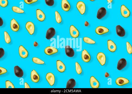 Avocado. Hintergrund aus isolierten Avocado-Stücken auf blauem Hintergrund. Flache Laie aus frischen reifen Avocados und Avacadostücken. Stockfoto