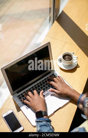 Morgen Der Tag beginnt mit einer Tasse Kaffee im Cafe und Surfen im Internet die neuesten Nachrichten im Internet. Afrikanische Frau in eine Kaffeerösterei dur Stockfoto