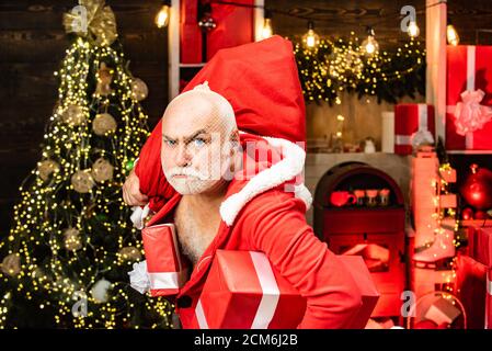 Gefährlicher Einbrecher in Santa-Kostüm gekleidet. Santa in der Maske mit Tasche. Lustige Santas mit Taschen - Einbrecher oder Dieb Konzept. Stockfoto