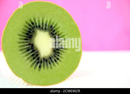 Nahaufnahme von geschnittenem, frisch geschnittenem Kiwi Obst isoliert Overlay mit Bokeh, verschwommenes Acryl Malerei mit rosa und weißen Farben Hintergrund. Speicherplatz kopieren. Stockfoto