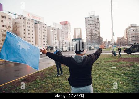 SANTIAGO, CHILE - 11. SEPTEMBER 2020 - EIN Mann protestiert mit einer Flagge mit dem mapuche-Stern 'wüñellfe', während die Polizei die Demonstration unterdrückt. Hundre Stockfoto