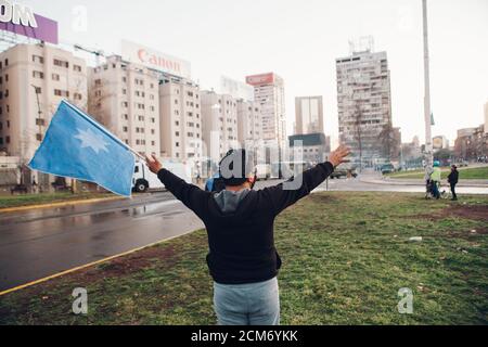 SANTIAGO, CHILE - 11. SEPTEMBER 2020 - EIN Mann protestiert mit einer Flagge mit dem mapuche-Stern 'wüñellfe', während die Polizei die Demonstration unterdrückt. Hundre Stockfoto