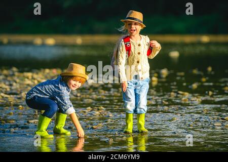 Kleines Paar in der Liebe spielen im Fluss. Kinder wandern im Fluss. Reisen und Trekking mit kleinen Kindern. Aktives Kind, das die Natur erkundet. Stockfoto