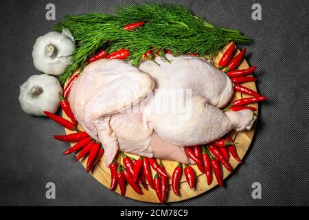 Ein halbes rohes Huhn serviert Gemüse, Knoblauch und rote Paprika, horizontal Stockfoto