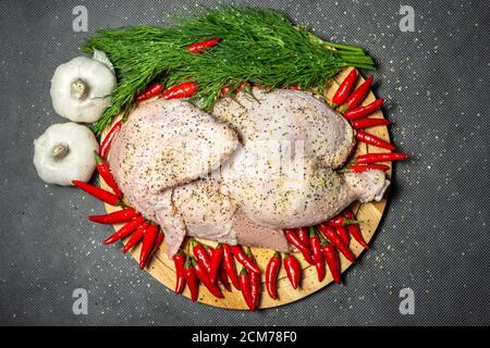 Ein halbes rohes Huhn serviert Gemüse, bestreut mit Gewürzen, horizontal Stockfoto