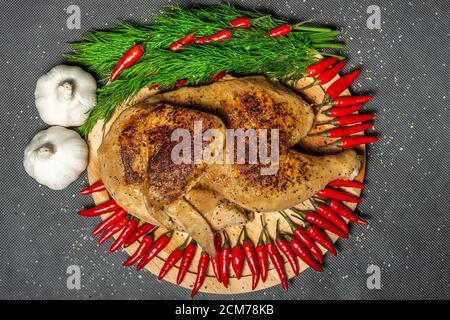 Gebratenes Huhn, gebratenes halbes Huhn, serviert Gemüse, bestreut mit Gewürzen, Knoblauch und roten heißen Mini-Pfeffer Stockfoto