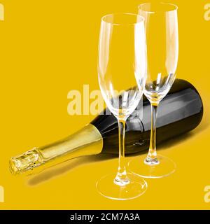Zwei Sektgläser und eine Flasche auf gelbem Hintergrund Stockfoto