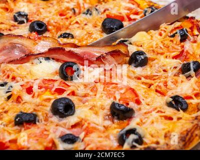 Machen Sie eine Pizza zu Hause mit Tomaten, Oliven, Schinken und Käse, Kochen zu Hause Konzept. Stockfoto