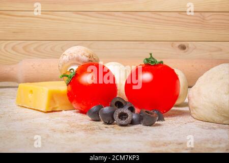 Hausgemachte Pizzazutaten Tomaten, Champignons, Käse, Oliven und Teig auf Holzhintergrund Stockfoto