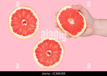 Männliche Hand mit Grapefruit auf rosa Hintergrund. Menschen lebendige Lebensstil, Konzept. Grapefruit-Set Stockfoto